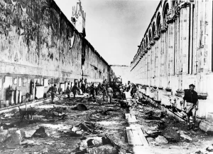 Historical World War II photograph inside the Camposanto Monumentale in Pisa, showing the debris-covered floor after the roof collapse and workers clearing the galleries next to damaged medieval frescoes.